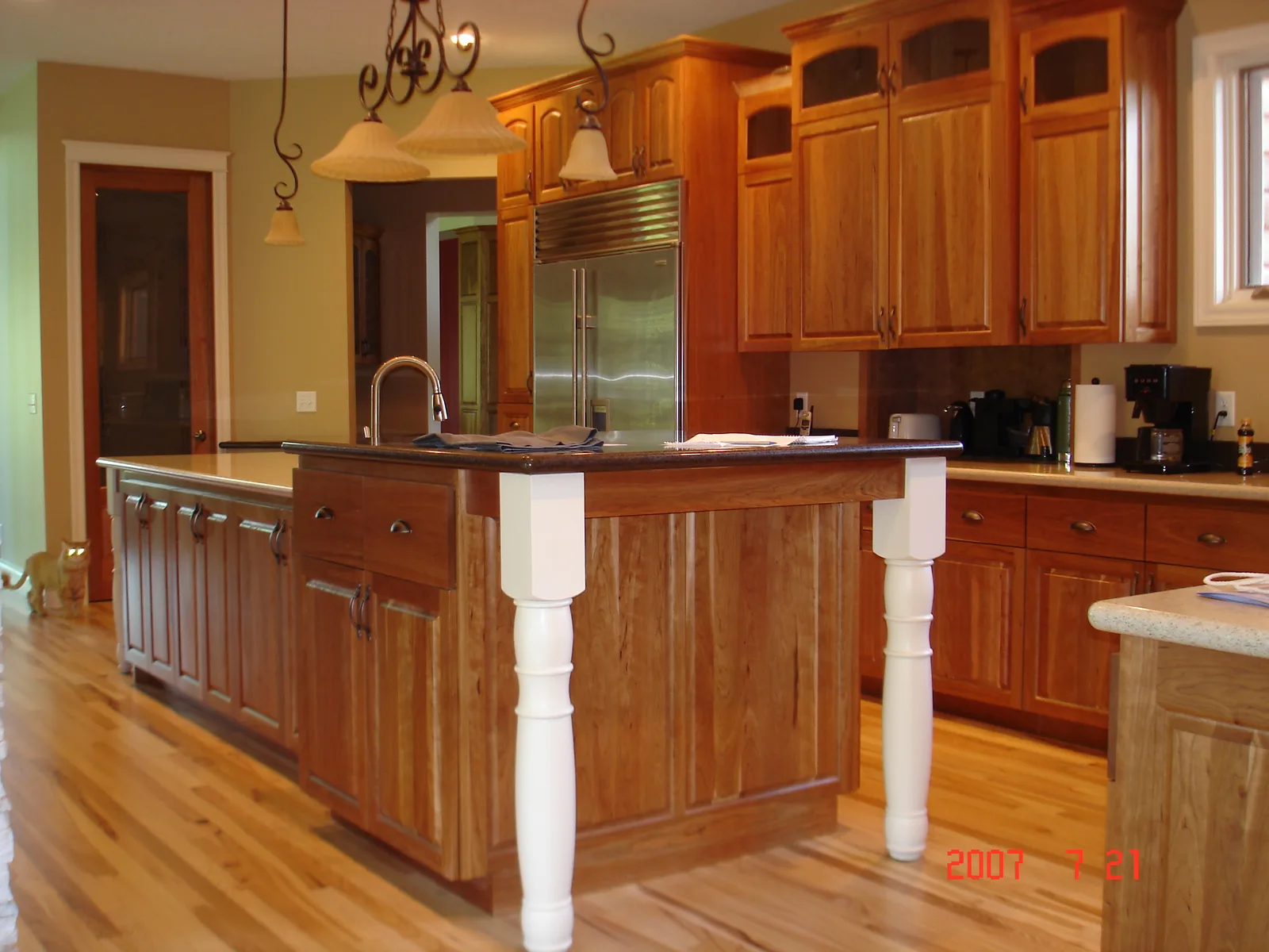 Custom cherry kitchen island with wrought iron pendant lighting, built by Kreuser Cabinets in Anoka, MN