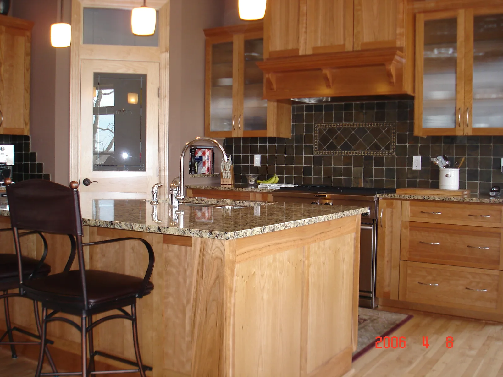 Custom maple kitchen cabinetry with slate tile backsplash and granite island