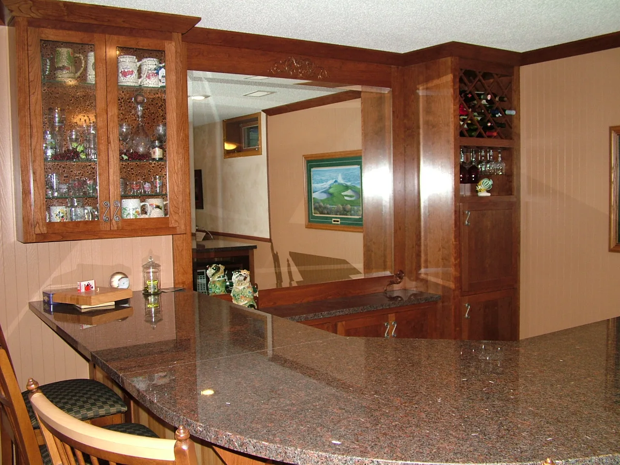 Custom home bar with wine rack, glass cabinet doors and granite counter
